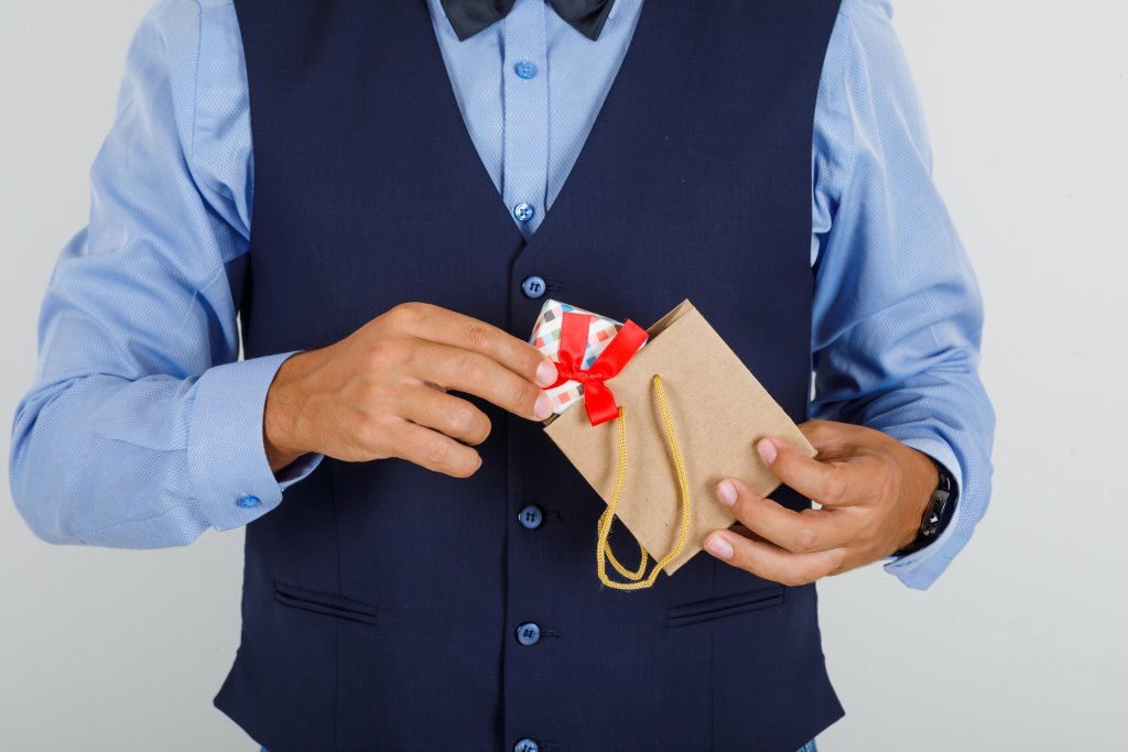 young-man-taking-present-out-of-paper-bag-in-suit.jpg